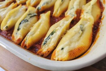 A bubbling hot baking dish of Authentic Italian Stuffed Shells in 1 Hour sits cooling on the kitchen counter.