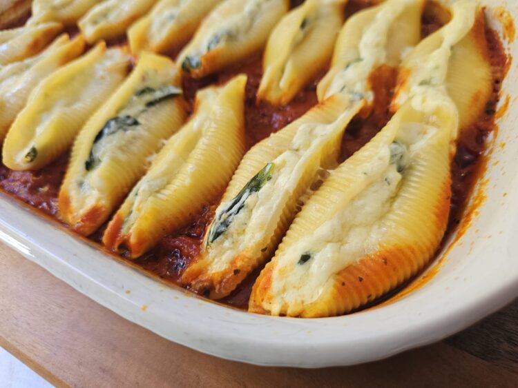 A bubbling hot baking dish of Authentic Italian Stuffed Shells in 1 Hour sits cooling on the kitchen counter.