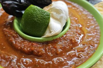 A bowl of Authentic Salsa Roja in 30 Minutes is surrounded by fresh corn tortilla chips.