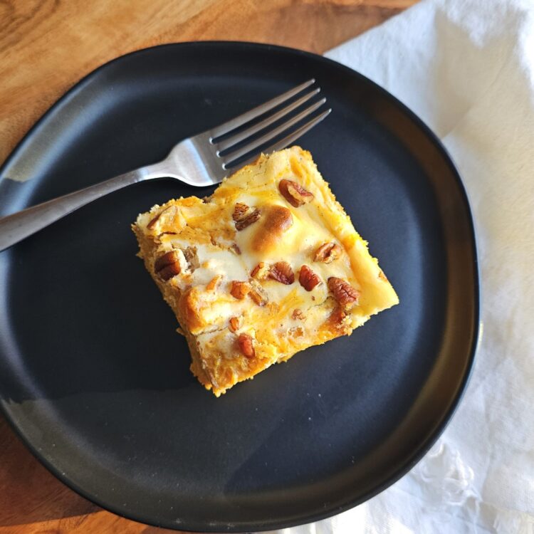 A slice of this easy as 1-2-3 Pumpkin Cheesecake Bread Pudding sits at the center of a plate.