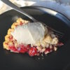 A slice of Old Fashioned Tart Cherry Pie is topped with a generous scoop of vanilla ice cream.