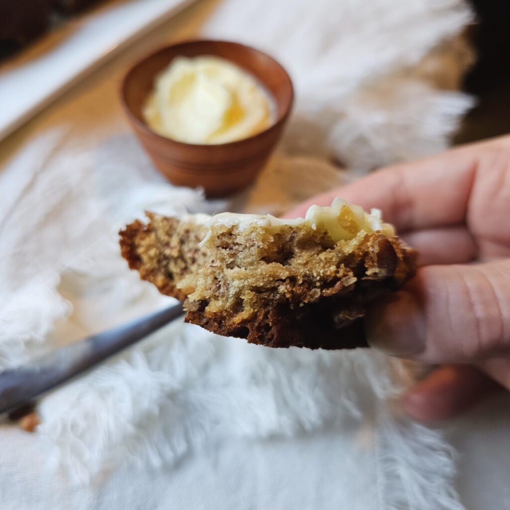 A slice of the Brown Sugar and Buttermilk Banana Bread is slathered in butter. In a playful spirit, there is a bite taken out of the slice.