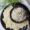 A small bowl is filled with this homemade tuna salad recipe. Saltine crackers are arranged on a plate.